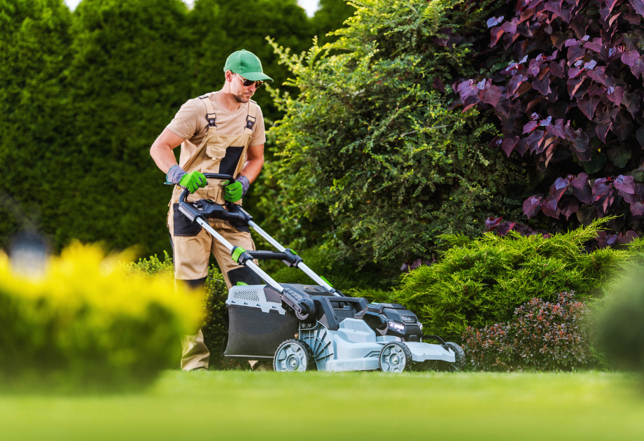man using a push mower on lawn